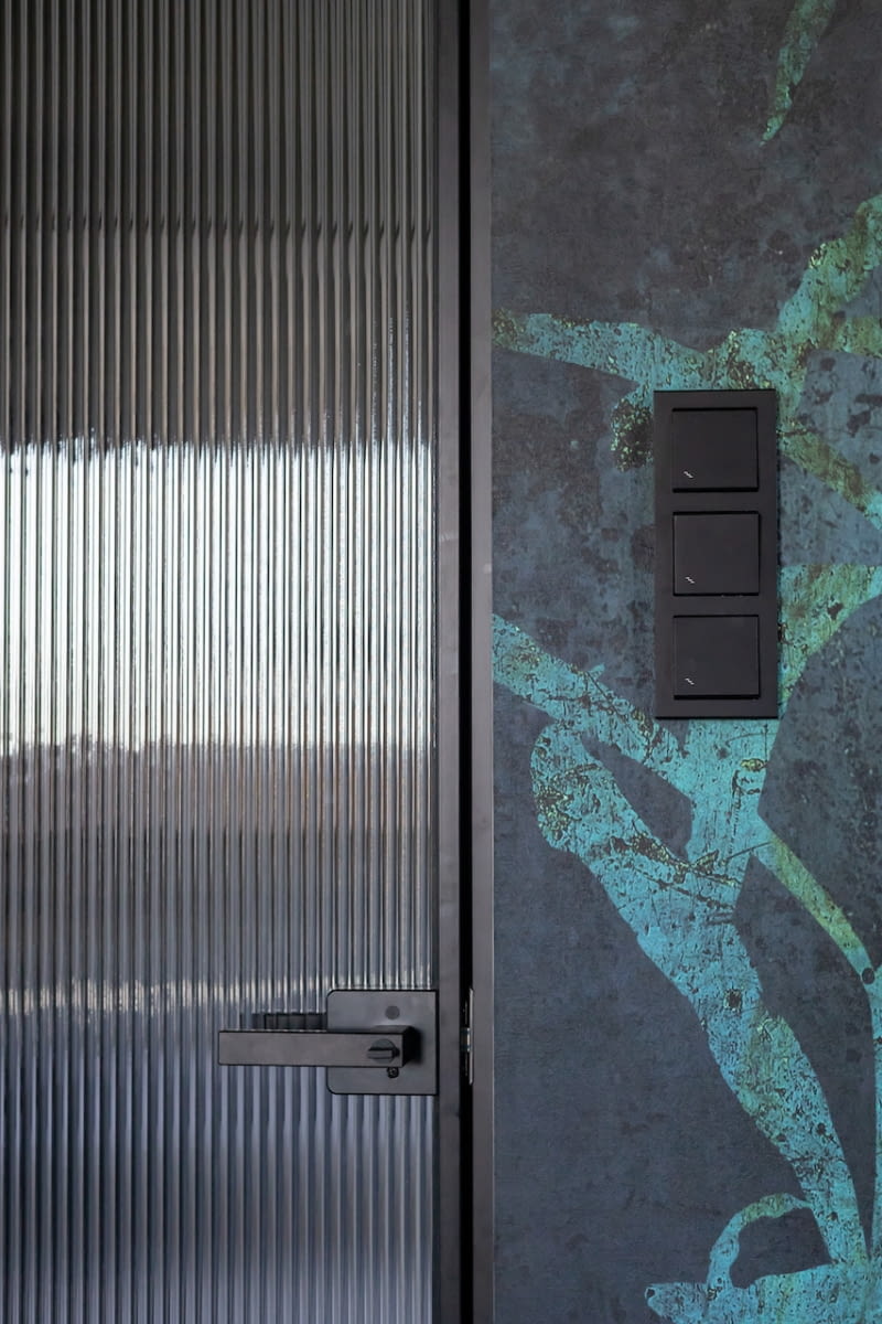 Drzwi do sypialni zdobi ryflowane szkło. W założeniu ma pełnić tę samą rolę co matowe szkło w drzwiach przesuwnych do łazienki – doświetlać ciemniejszą przestrzeń, którą jest poprzedzający sypialnię korytarz.