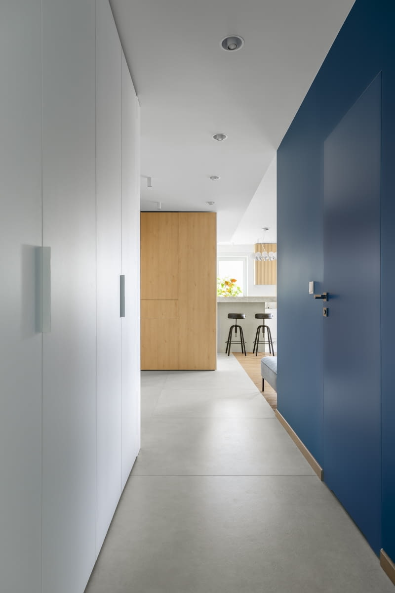 Wyrazista, niebieska ściana w korytarzu – zostały w niej ukryte drzwi do toalety. Wyrazista, niebieska ściana w korytarzu – zostały w niej ukryte drzwi do toalety.
