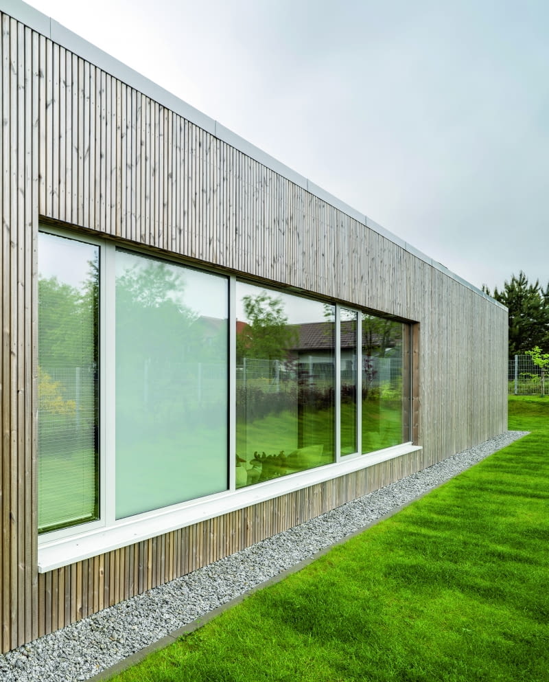 Duże okna otwierają budynek od strony wewnętrznego dziedzińca, ale zdecydowano się też na wzbogacenie nimi wystawionej na świat elewacji północnej, kryjącej wejścia do sypialni
