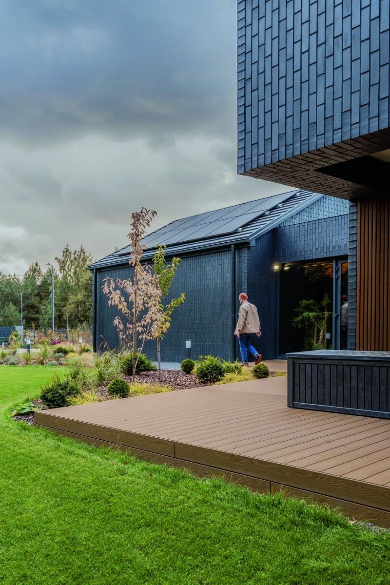 Wrażenie, jakie robi ciemny klinkier, w który dosłownie owinięto ten dom, potęgują połacie dachowe, obłożone bardzo zbliżoną kolorystycznie blachodachówką – oraz moduły fotowoltaiczne, jakby z tej samej monochromatycznej linii wzorniczej. Gdy nad budynek nadciągają stalowoszare, nisko operujące chmury, efekt zostaje podniesiony do kwadratu... Wrażenie, jakie robi ciemny klinkier, w który dosłownie owinięto ten dom, potęgują połacie dachowe, obłożone bardzo zbliżoną kolorystycznie blachodachówką – oraz moduły fotowoltaiczne, jakby z tej samej monochromatycznej linii wzorniczej. Gdy nad budynek nadciągają stalowoszare, nisko operujące chmury, efekt zostaje podniesiony do kwadratu...