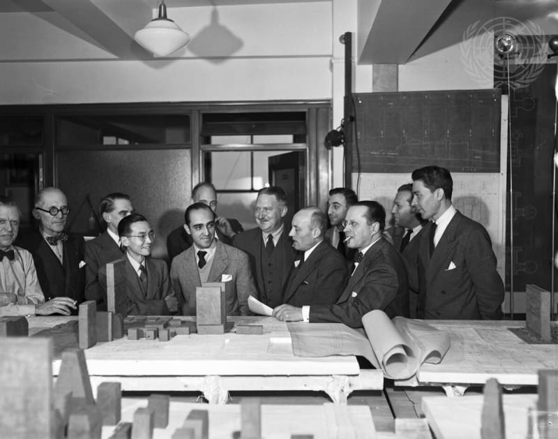 Zdjęcie z 1947 roku. Wallace K. Harrison, czwarty od lewej, główny planista siedziby ONZ, przed wstępnymi modelami wraz z członkami Rady Konsultantów ds. Projektowania oraz innymi konsultantami powołanymi do pomocy przy opracowaniu planów budowy stałej siedziby ONZ. Członkowie Rady stojący na pierwszym planie, od lewej: Ssu-Cheng Liang (Chiny), Oscar Niemeyer (Brazylia), Nikolai Bassov (ZSRR) i Ernest Cormier (Kanada). W drugim rzędzie, od lewej: Sven Markelius (Szwecja), Charles Le Corbusier (Francja), członek Rady Bodiansky (Francja), inżynier-konsultant dyrektora, Wallace K. Harrison, G.A. Foilleux (Australia), Max Abramowitz, dyrektor ds. planowania z USA, oraz konsultanci: Ernest Weismann (Jugosławia), Antoniades (Grecja) i Maciej Nowicki (Polska). Zdjęcie z 1947 roku. Wallace K. Harrison, czwarty od lewej, główny planista siedziby ONZ, przed wstępnymi modelami wraz z członkami Rady Konsultantów ds. Projektowania oraz innymi konsultantami powołanymi do pomocy przy opracowaniu planów budowy stałej siedziby ONZ. Członkowie Rady stojący na pierwszym planie, od lewej: Ssu-Cheng Liang (Chiny), Oscar Niemeyer (Brazylia), Nikolai Bassov (ZSRR) i Ernest Cormier (Kanada). W drugim rzędzie, od lewej: Sven Markelius (Szwecja), Charles Le Corbusier (Francja), członek Rady Bodiansky (Francja), inżynier-konsultant dyrektora, Wallace K. Harrison, G.A. Foilleux (Australia), Max Abramowitz, dyrektor ds. planowania z USA, oraz konsultanci: Ernest Weismann (Jugosławia), Antoniades (Grecja) i Maciej Nowicki (Polska).