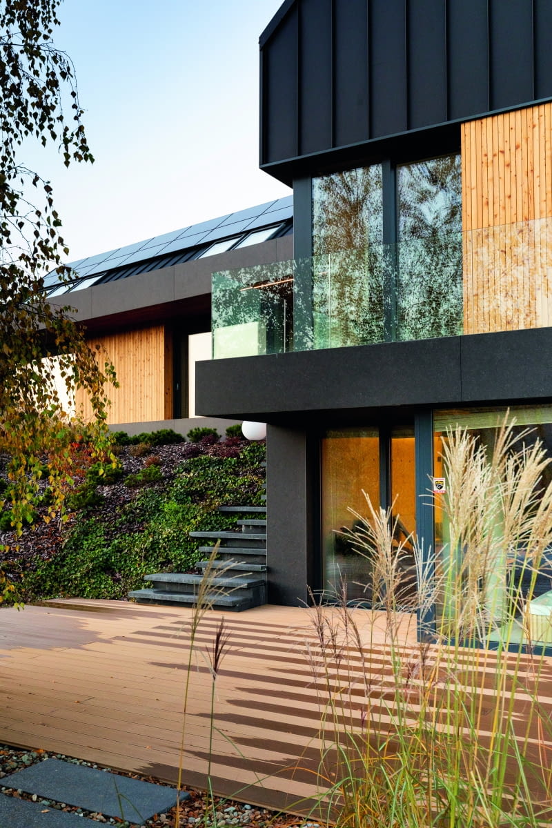 Szkło jest cichym bohaterem tej realizacji. Dzięki niemu wnętrza  otwierają się na bogate przyrodniczo otoczenie domu,  a jednocześnie przyjmują mnóstwo słońca – również poprzez  zamontowane w dachu okna połaciowe.