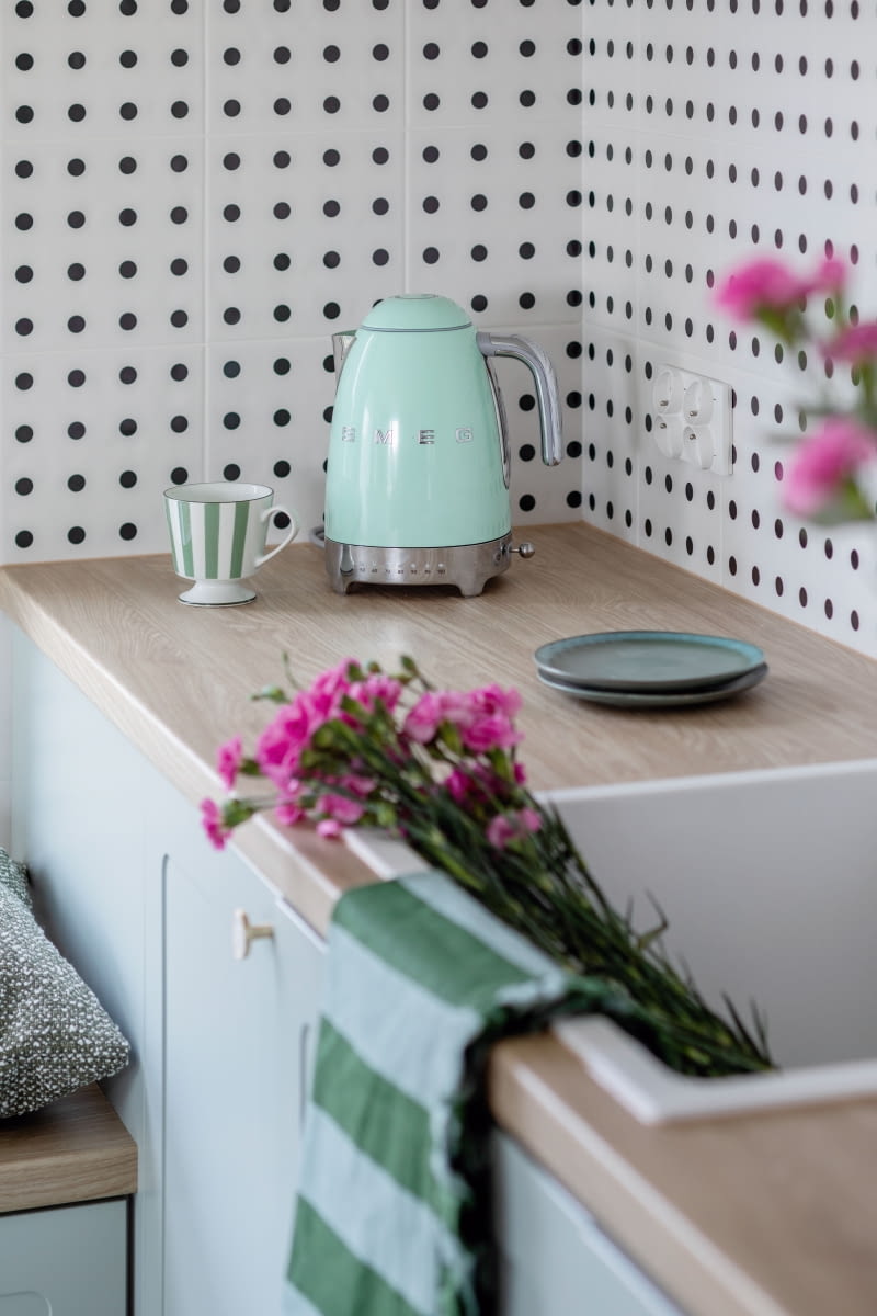 Szafki kuchenne stolarz wykonał z lakierowanych, matowych płyt – dolnych w kolorze szałwii, a górnych beżu. Na blaty wybrano laminowaną płytę imitującą wzór drewna. Okrągłe, mosiężne gałki meblowe nawiązują kształtem do powtarzanych w całym mieszkaniu kropek. Błyszczą delikatnie od wypełniającej je masy perłowej. Szafki kuchenne stolarz wykonał z lakierowanych, matowych płyt – dolnych w kolorze szałwii, a górnych beżu. Na blaty wybrano laminowaną płytę imitującą wzór drewna. Okrągłe, mosiężne gałki meblowe nawiązują kształtem do powtarzanych w całym mieszkaniu kropek. Błyszczą delikatnie od wypełniającej je masy perłowej.