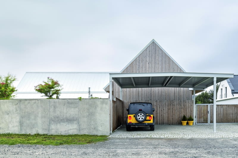 Początkowo garaż miał znajdować się w obrębie bryły, ale ostatecznie postanowiono wnętrza przeznaczyć wyłącznie dla mieszkańców, a miejsce parkingowe „wystawić” na zewnątrz, tuż koło surowego, betonowego muru