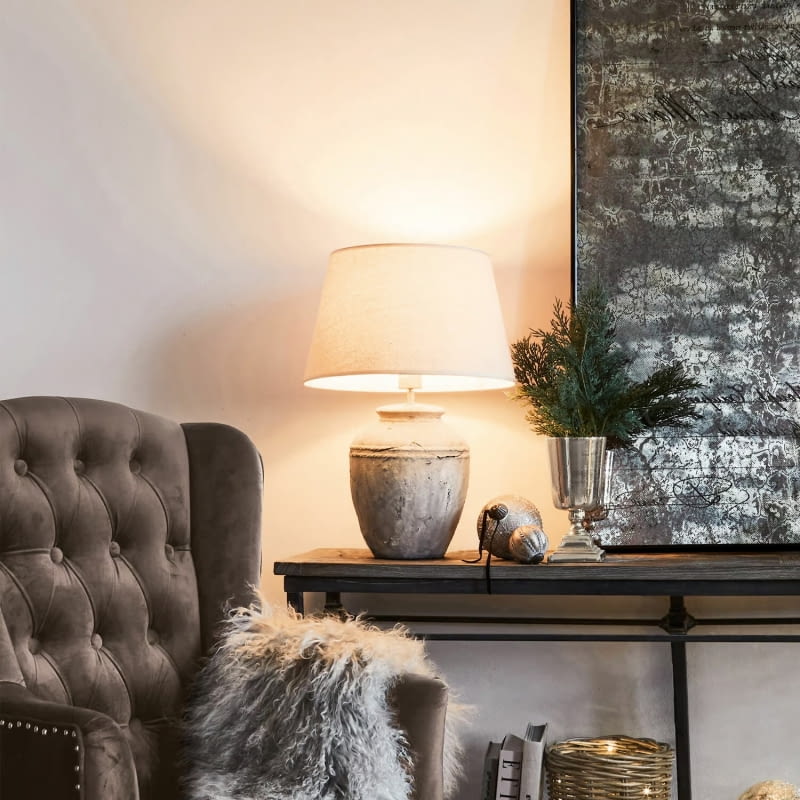 Ceramiczna podstawa lampy Mosnay przypomina wazę ze starego betonu, wraz z lnianym kloszem tworzy dekorację idealną do klasycznego wnętrza.