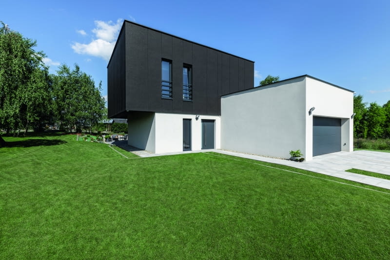 Wydawać się może, że ten dom wręcz pączkuje swobodnie rozrzuconymi bryłami, ale tak naprawdę całość organizuje obszerny prostokąt parteru  wypełniony otwartą przestrzenią, który od frontu wygląda bardzo niepozornie, niczym wciśnięty i sprasowany od góry dodatek do reszty