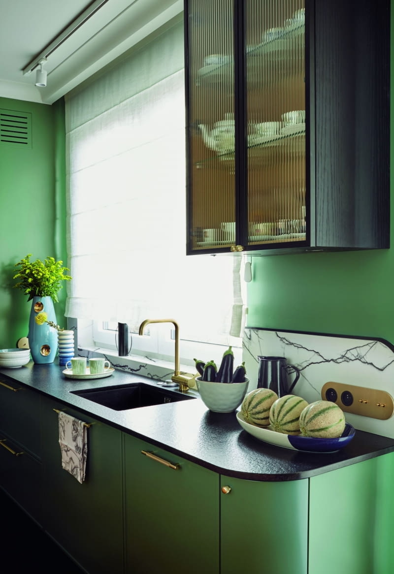 Złoto pojawia się też jako kolor wykończenia baterii zlewozmywakowej oraz gniazdek elektrycznych nad blatem. Nutę nonszalancji wprowadzają płytki ścienne z serii B&W Marble marki Florim, które naśladują marmur. Na blacie kuchennym stanęła wyjątkowa ceramika: wazony od Malwiny Konopackiej – OKO Gold i NANA, a także czarny dzbanek Conco i duża misa na owoce ze sklepu TK Maxx.