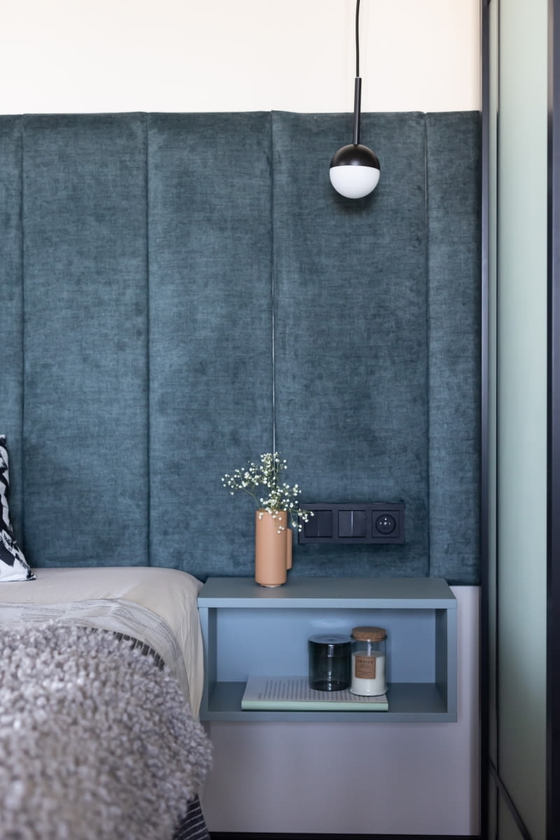 Niebieskie półki przy łóżku oraz toaletka zamontowana na ścianie garderoby powstały na zamówienie. Stolarz wykonał je z lakierowanej płyty meblowej. Niewielkie meble o prostej bryle idealnie wpasowują się w nowoczesną aranżację wnętrza.
