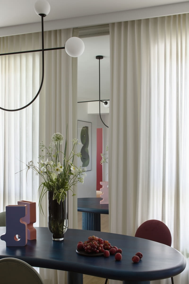 Wąską ścianę, przy której ustawiono stół wykończono wysokim do sufitu pasem lustra, co nadaje głębi pomieszczeniu.