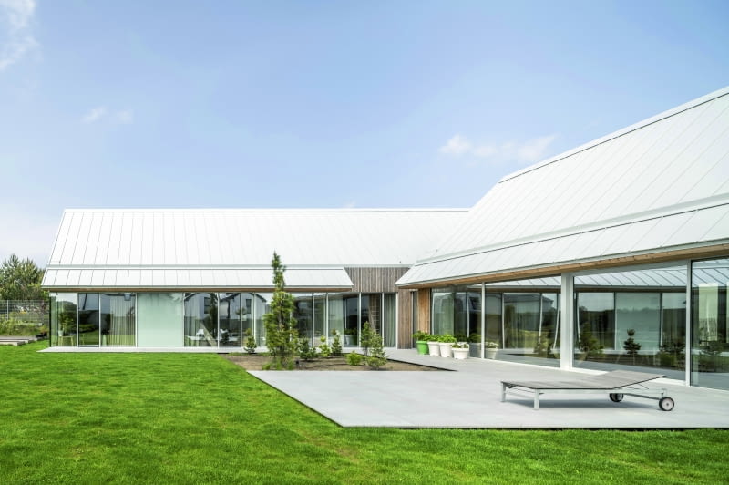 Sercem przestrzeni zewnętrznej, „pozadomowej”, jest rozległa powierzchnia wykreowana między dwoma skrzydłami budynku, która łączy w sobie funkcje tarasu, trawnika i swoistego placu-agory do działań wszelakich