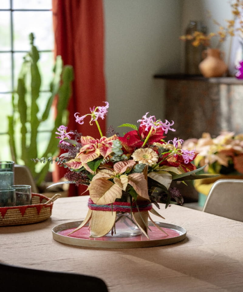 Suszone torebki nasienne palmy, przywiązane sznurkiem do zewnętrznej strony szklanego wazonu, dodają egzotyczności. Efektem jest barwna kompozycja, która łączy tropikalny klimat z pięknem zimowych kwiatów.