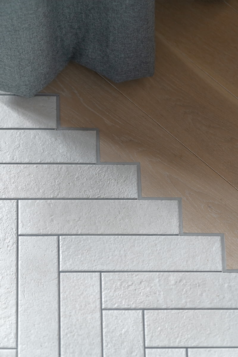 W całym mieszkaniu podłogę wykończono płytkami ceramicznymi z FAP Ceramiche ułożonymi w jodełkę oraz bielonymi, dębowymi deskami kupionymi w sklepie Deska Design. Architektom zależało, żeby przejście w holu pomiędzy tymi dwoma materiałami było ozdobne. Na krawędzi płytek wyeksponowano więc wzór, do którego montażyści podłogi precyzyjnie docięli deski. Styk wypełnili elastyczną fugą Sikaflex. W całym mieszkaniu podłogę wykończono płytkami ceramicznymi z FAP Ceramiche ułożonymi w jodełkę oraz bielonymi, dębowymi deskami kupionymi w sklepie Deska Design. Architektom zależało, żeby przejście w holu pomiędzy tymi dwoma materiałami było ozdobne. Na krawędzi płytek wyeksponowano więc wzór, do którego montażyści podłogi precyzyjnie docięli deski. Styk wypełnili elastyczną fugą Sikaflex.