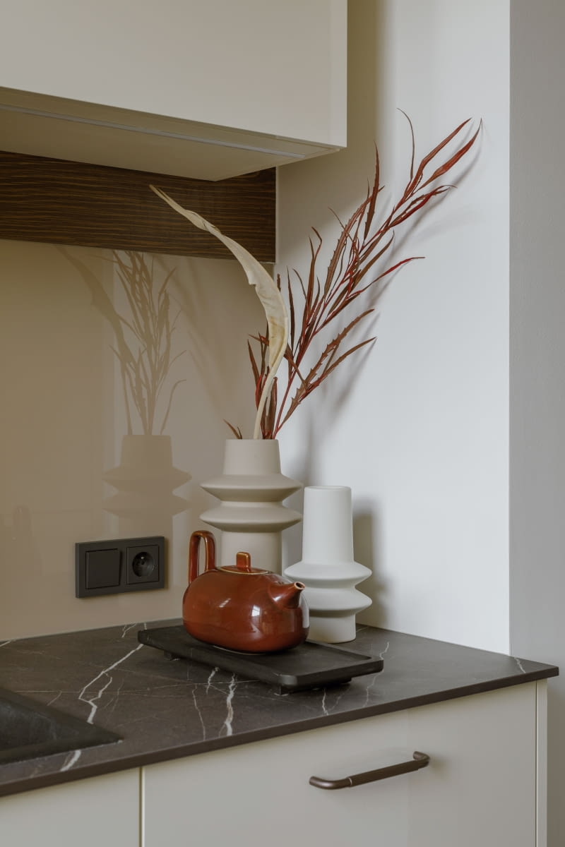 Cienki, jak przystało na nowoczesną kuchnię, ale jednocześnie wytrzymały blat z kompozytu imituje kamień. Odcień ciemnego brązu ze wzorem jasnego użylenia idealnie komponuje się z białymi frontami szafek.