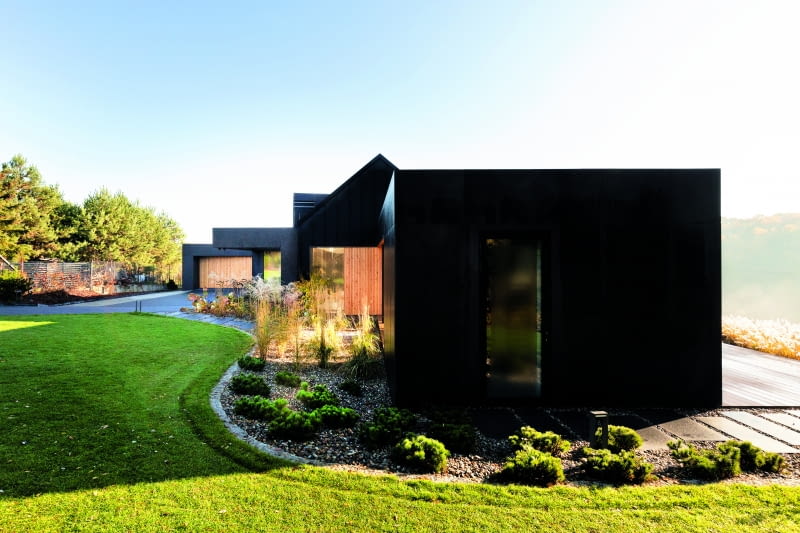 Po czym poznać sprawność architektów? Choćby po takich  właśnie „sztuczkach″. Część frontowa widziana z boku, od strony  bryły nakrytej dachem płaskim, wygląda jak parterowe osiedle  wzniesione gdzieś na amerykańskiej prerii, z tajemniczych  czarnych materiałów.