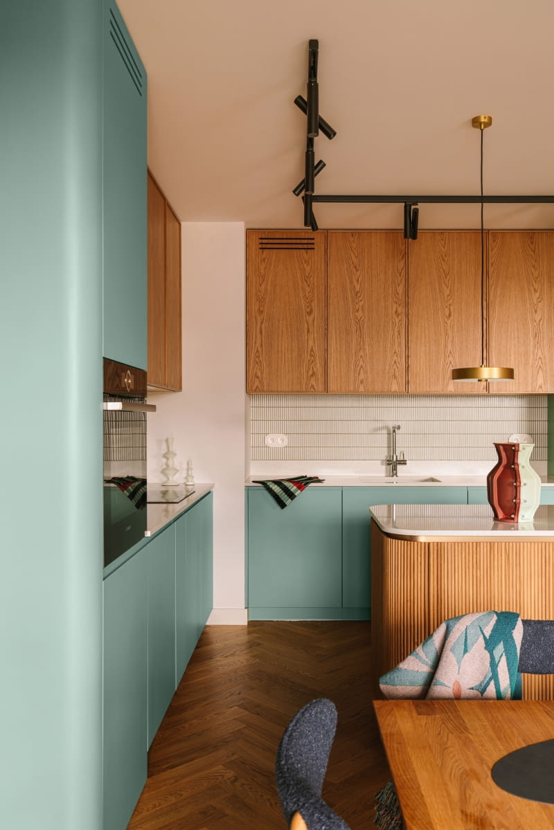 Zabudowę kuchenną uzupełniają blaty z konglomeratu wzbogaconego delikatnie połyskującym kruszywem, co dodaje im lekkości i wdzięku.