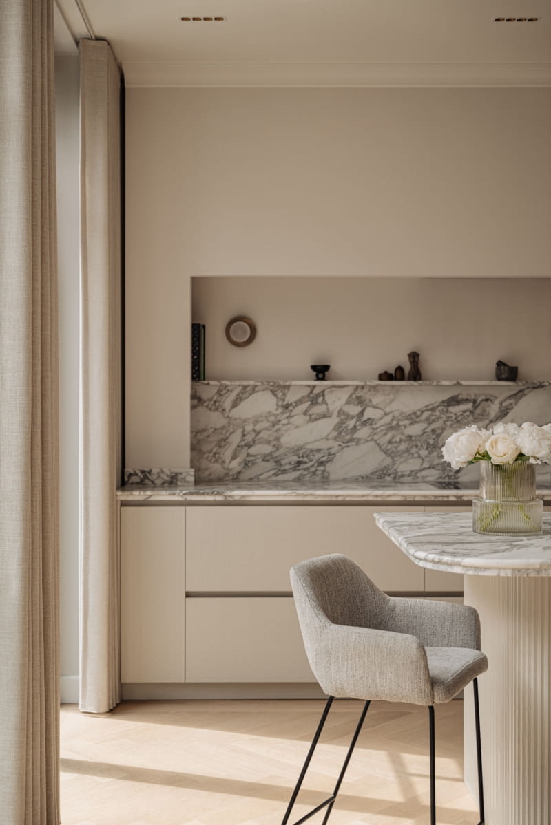 W kuchni detale, takie jak zaokrąglony marmurowy blat wyspy kuchennej, tworzą sprytną grę symetrii i asymetrii. Tara Ultra w kolorze Brushed Dark Platinum doskonale komponuje się z ciemnobrązowymi frontami kuchni.