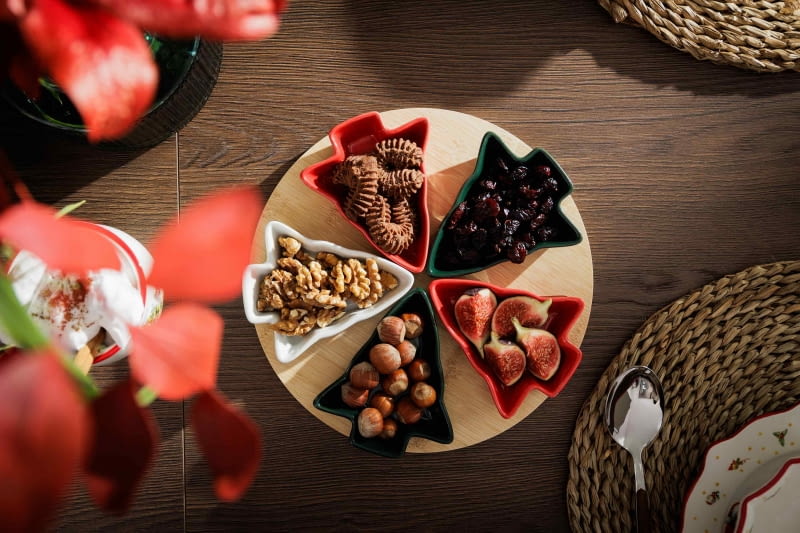 Ułożone na okrągłej desce miseczki w kształcie choinek urozmaicą aranżację stołu.