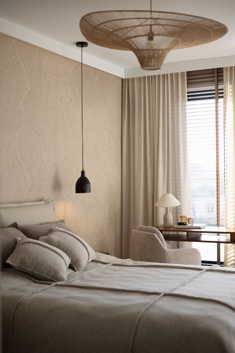 Główną dekoracją sypialni jest tapeta marki Arte ze sklepu Arcydom w stylu boho. Jej powierzchnię kształtują gęsto połączone sznurki, które układają się w wyraźny, trójwymiarowy relief wyczuwalny pod palcami. Nieregularne linie wzoru zawracają i zmieniają kierunek, co tworzy dynamiczny obraz.