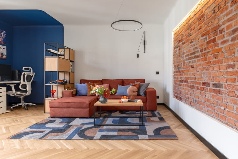 Biurko oddzielone jest od strefy relaksu na sofie ażurowym regałem