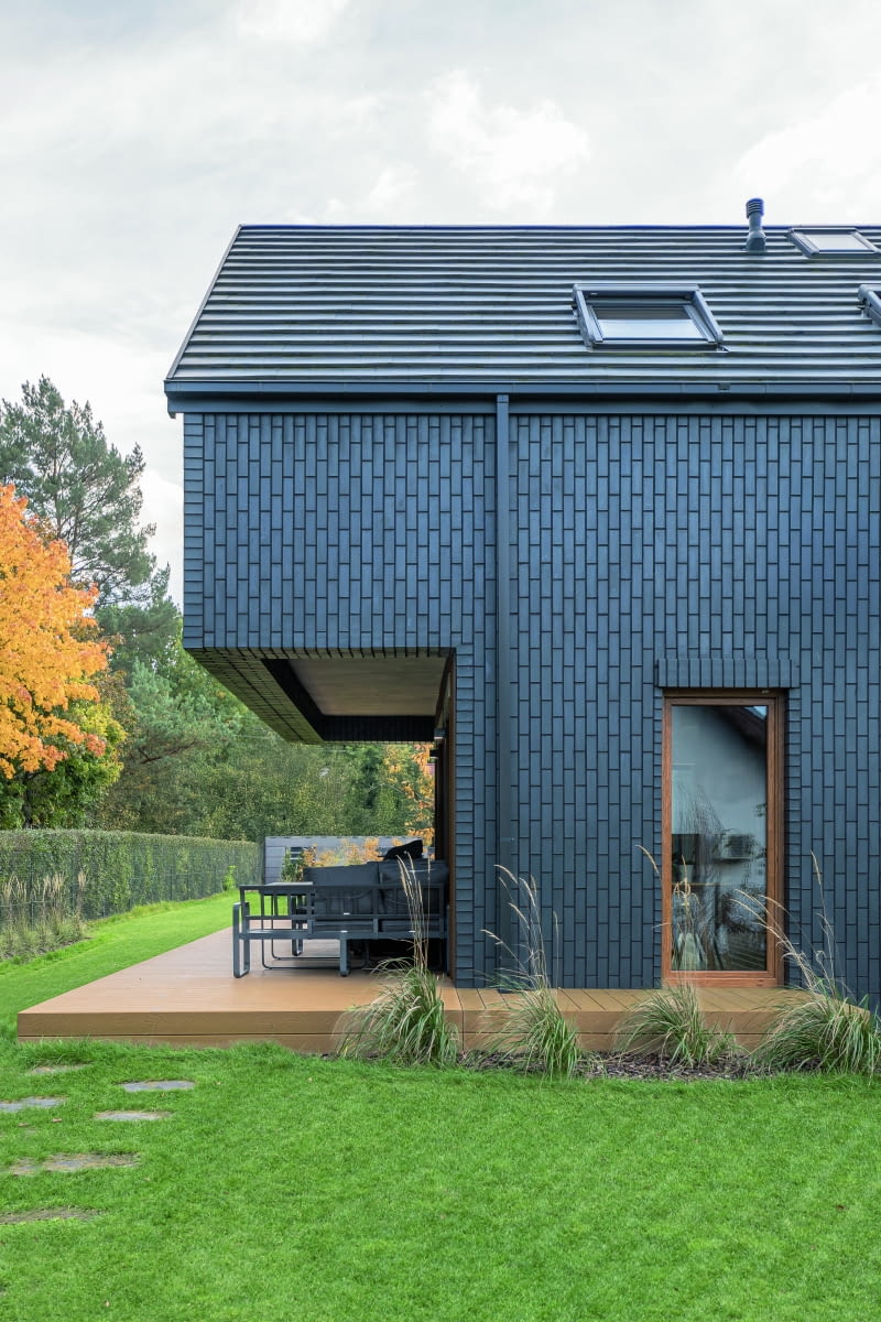 Obszerny podcień wykonany w parterze skrzydła mieszkalnego stworzył przestrzeń dla zadaszonego tarasu, w którym m.in. na posadzce zastosowano łatwe w utrzymaniu drewno kompozytowe Obszerny podcień wykonany w parterze skrzydła mieszkalnego stworzył przestrzeń dla zadaszonego tarasu, w którym m.in. na posadzce zastosowano łatwe w utrzymaniu drewno kompozytowe