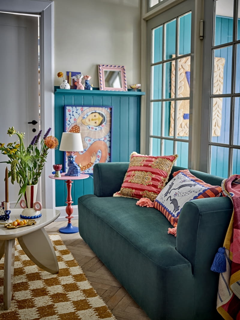 Ciemnozielony kolor sofy delikatnie uspokaja bardzo kolorowe wnętrze. Jednocześnie tworzy idealne tło dla wzorzystych poduszek. Ciemnozielony kolor sofy delikatnie uspokaja bardzo kolorowe wnętrze. Jednocześnie tworzy idealne tło dla wzorzystych poduszek.