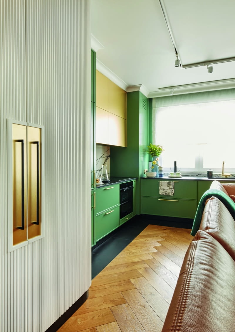 Kuchnia to ulubiona część pani domu. Gospodyni codziennie zachwyca się współgrającymi tu ze sobą kolorami zieleni i złota przełamanymi bielą oraz czernią. Zielone szafki w zgaszonym, matowym odcieniu elegancko komponują się z czarnym blatem z płomieniowanego granitu i ze złotymi uchwytami.