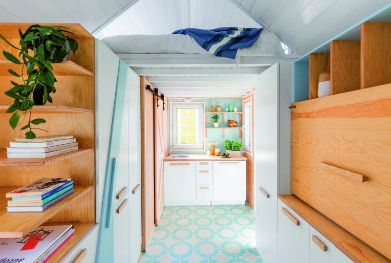 Wnętrze domku jest jasne – dużo jest bieli z błękitnymi akcentami  i ciepłych odcieni naturalnego drewna. Choć domek jest nieduży, każdy centymetr został wykorzystany, dzięki czemu wygodnie pomieszczą się w nim 4 osoby. Większość elementów wyposażenia wnętrza została wykonana ręcznie, na wymiar, z drewna oraz wytrzymałej (i modnej) sklejki.