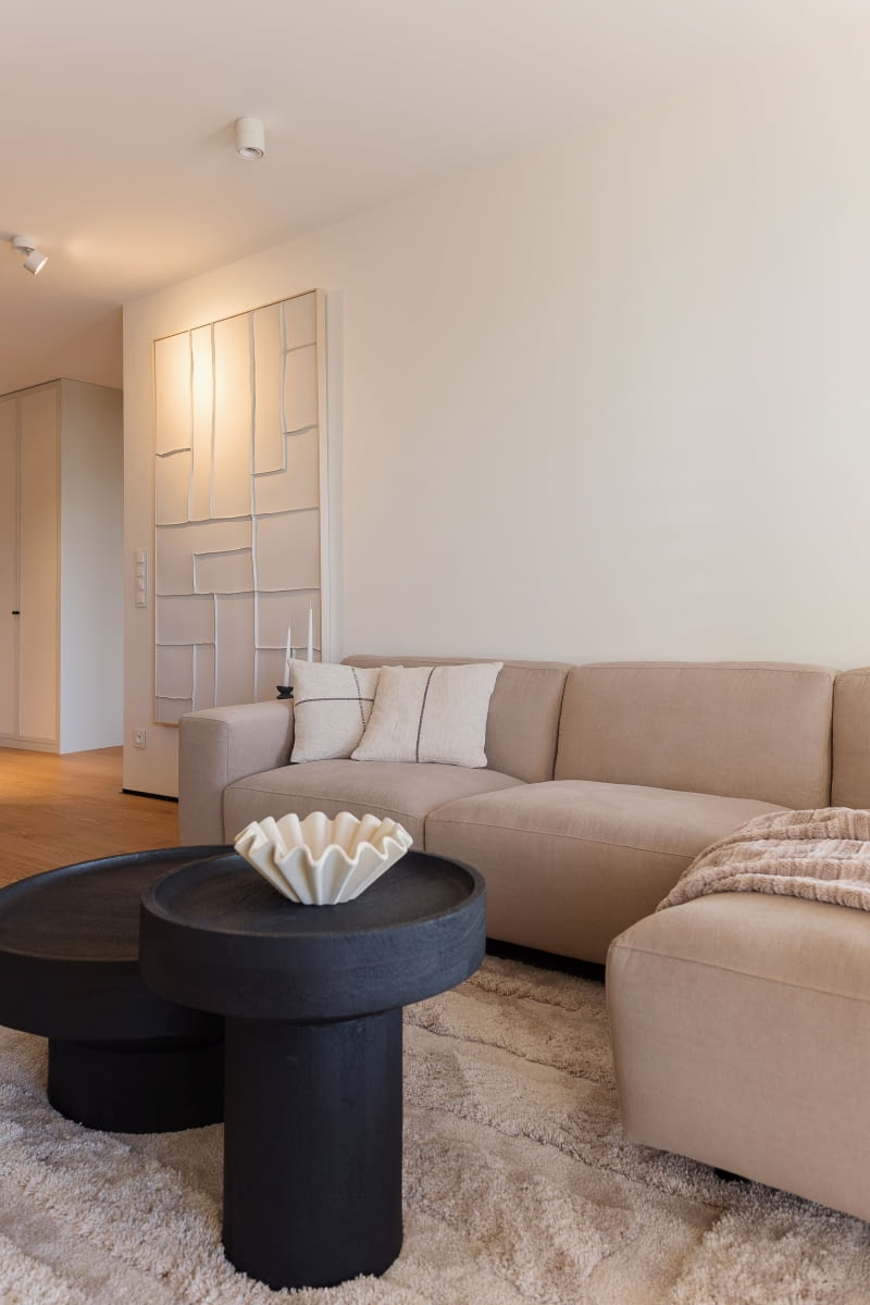 W części wypoczynkowej miękka sofa Vesta marki MTI Furninova ze sklepu almidesign.pl od razu wprowadza w tryb pełnego relaksu. Puszysty dywan z długim włosiem i czarne stoliki kupiono w Westwing. Całość spina duży obraz na lnianym płótnie z geometry-cznym motywem z kavehome.com – od początku planowany w tym miejscu, wraz z oświetlającym go reflektorem kierunkowym. Naprzeciwko stanęła komoda RTV z puvodesign.pl, ciemna, o orzechowym odcieniu, z frezowanymi łukami i masywnymi nogami-kolumnami, która porządkuje strefę wokół telewizora.