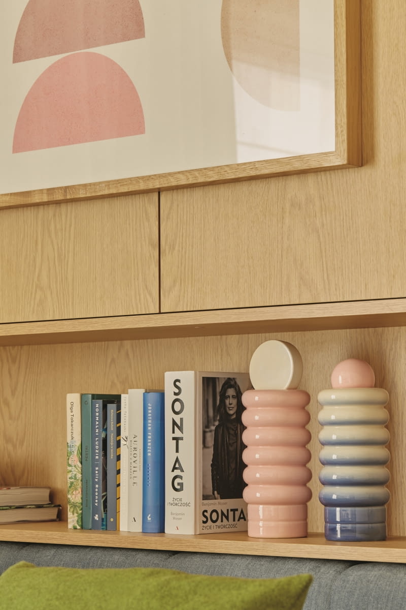 Największym dylematem do rozwikłania było tu zagospodarowanie przestrzeni wokół łóżka. Mebel mógł stanąć tylko w jednym miejscu pokoju, co wiązało się z koniecznością zaaranżowania za jego wezgłowiem sporej, asymetrycznej przestrzeni. Powstała więc tu zabudowa meblowa z praktycznymi półkami do przechowywania. Ich ozdobą są ceramiczne niebieskie i różowe wazony NANA Formy autorstwa Malwiny Konopackiej.