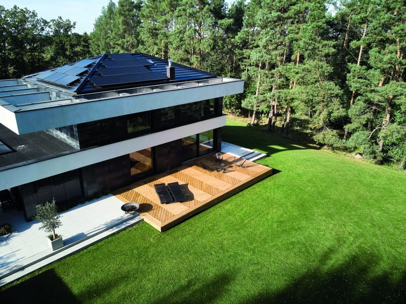 Masywne betonowe opaski poszerzają optycznie budynek, dostarczając przy okazji nieco cienia na obu kondygnacjach i kontrastując czerń kamienia elewacyjnego bielą tynku