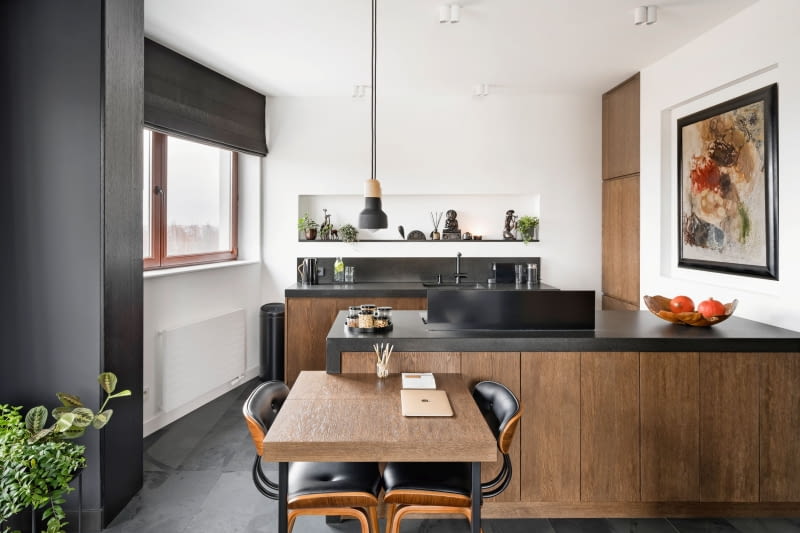 Zamiast dominujących we wnętrzu górnych szafek ściany w kuchni zdobią wykonane z pomocą przedścianek, ozdobne, podświetlane wnęki. W najdłuższej z nich stoją pamiątki z podróży po Azji. Ich wybór i kolejność ustawienia są dokładnie przemyślane. W drugiej wnęce znalazł się obraz Edwarda Nadulskiego, prezent od taty. W domu rodzinnym projektantki zawsze było dużo obrazów. Kilka z nich rodzice przekazali córce. Zostały umieszczone w idealnie zaplanowanych do tego miejscach.