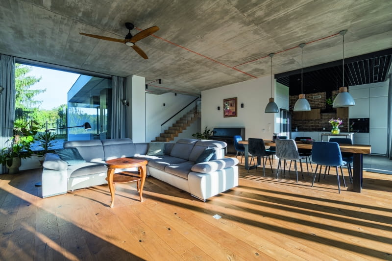 W przylegającej do salonu kuchni centralne miejsce zajmuje wyspa z granitowym blatem, specjalnie zamówionym w zakładzie kamieniarskim.  Na podłodze leżą włoskie płytki firmy Imola Ceramica, a ścianę w głębi efektownie pokryto ćwiartkami cegieł. Kratownica u góry to sufit rastrowy,  często spotykany w sklepach czy magazynach – dobrze wpisuje się w industrialny charakter wnętrz