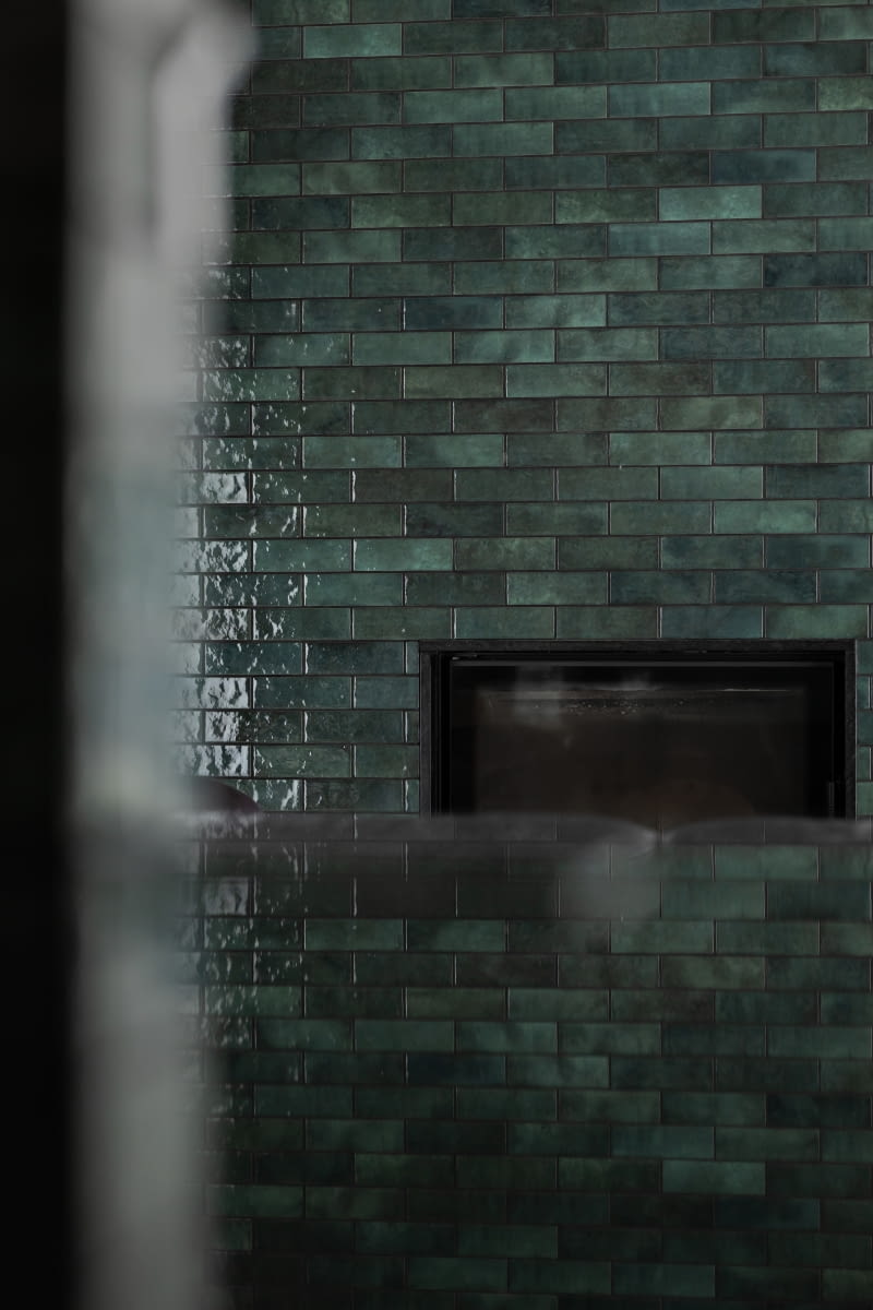 Kominek zdobią te same, co użyte na murku między kuchnią a jadalnią, zielone płytki-cegiełki. Stanowią spajający aranżację, powtarzalny akcent wystroju. Kominek zdobią te same, co użyte na murku między kuchnią a jadalnią, zielone płytki-cegiełki. Stanowią spajający aranżację, powtarzalny akcent wystroju.