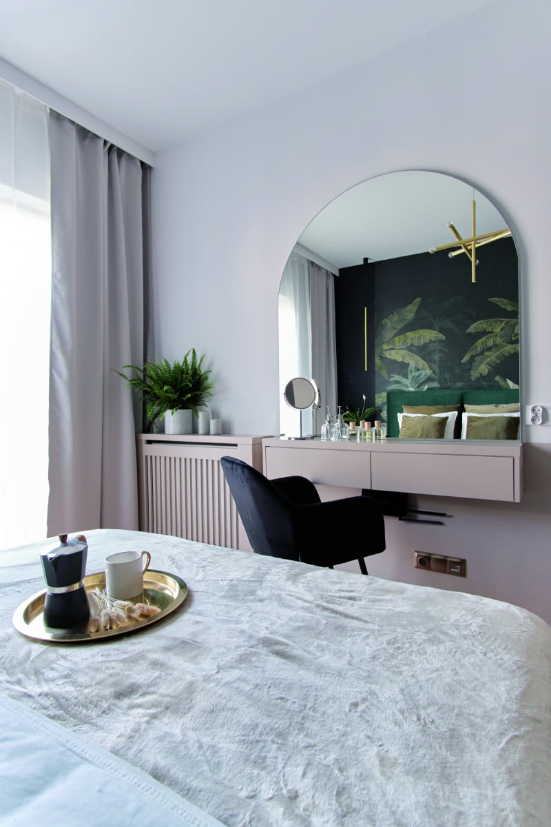 SYPIALNIA MULTIZADANIOWA. Dzięki temu, że sypialnia ta miała "fajny" metraż, Agnieszka mogła sobie pozwolić na podział tego pomieszczenia na część przeznaczoną do spania oraz miejsce do codziennej pielęgnacji urody. Konkretnie zaplanowała tam niedużą konsolę ze sporym lustrem. W tym wnętrzu miała zgodę Dominiki na użycie ciemniejszych kolorów – stąd czarna, pojemna szafa, a także ciekawa wzorniczo, nieco kontrastowa tapeta/mural na jednej ze ścian.