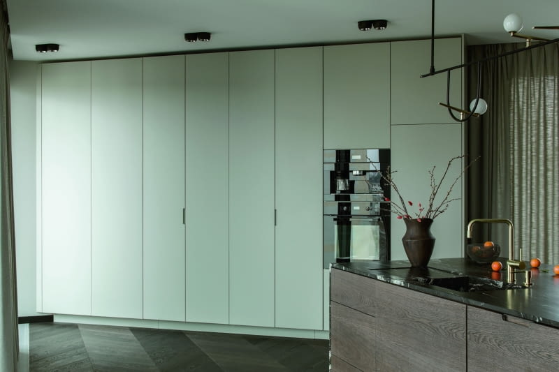 Zamknięcie skrzydła szafek kuchennych pozwalają całkowicie ukryć wnękę. Takie rozwiązanie umożliwia system okuć Hawa marki PEKA — drzwi najpierw otwierają się tradycyjnie, po czym obracają się o 90° i wsuwają do wąskich kaset, dzięki czemu w przestrzeni nie pozostają żadne przeszkadzające, otwarte skrzydła szafek. Zamknięcie skrzydła szafek kuchennych pozwalają całkowicie ukryć wnękę. Takie rozwiązanie umożliwia system okuć Hawa marki PEKA — drzwi najpierw otwierają się tradycyjnie, po czym obracają się o 90° i wsuwają do wąskich kaset, dzięki czemu w przestrzeni nie pozostają żadne przeszkadzające, otwarte skrzydła szafek.