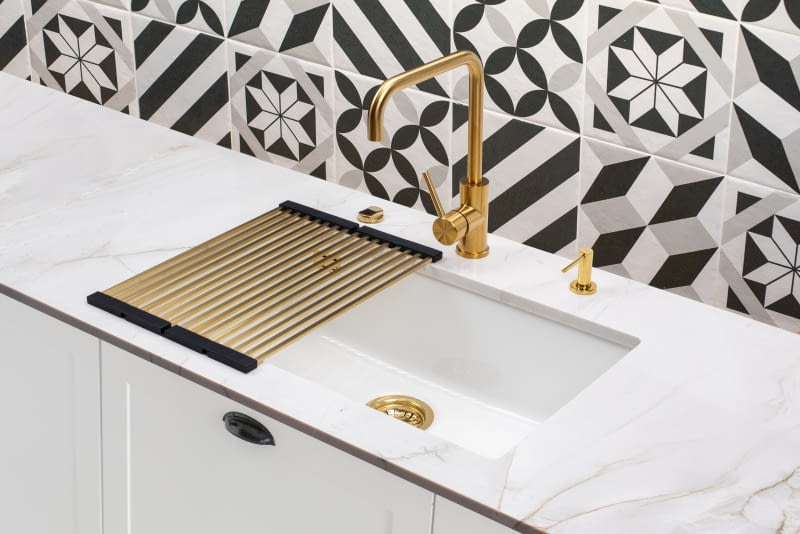 Złota bateria dobrze zaprezentuje się w towarzystwie białego zlewozmywaka i białej zabudowy kuchennej. Będzie też współgrać z innymi dodatkami w tym kolorze.