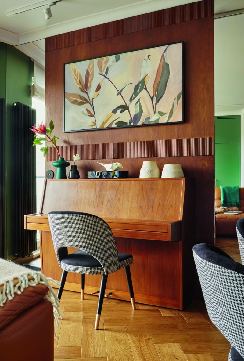 Pianino to bardzo ważny mebel w życiu rodziny. Codziennie gra na nim pan domu i jego trzej synowie. Architektka umieściła je na tle specjalnie dobranej kolorystycznie do instrumentu fornirowanej płyty. Z dwóch stron mebla umieszczono tafle luster, które nadają gabarytowemu meblowi nieco lekkości. Instrument pełni też rolę ekspozycji ładnych dekoracji: jasne wazony stworzyła artystka Alicja Patanowska, ciemne wazony i nakrapiany ptak Aczi pochodzą od Noti Studio.