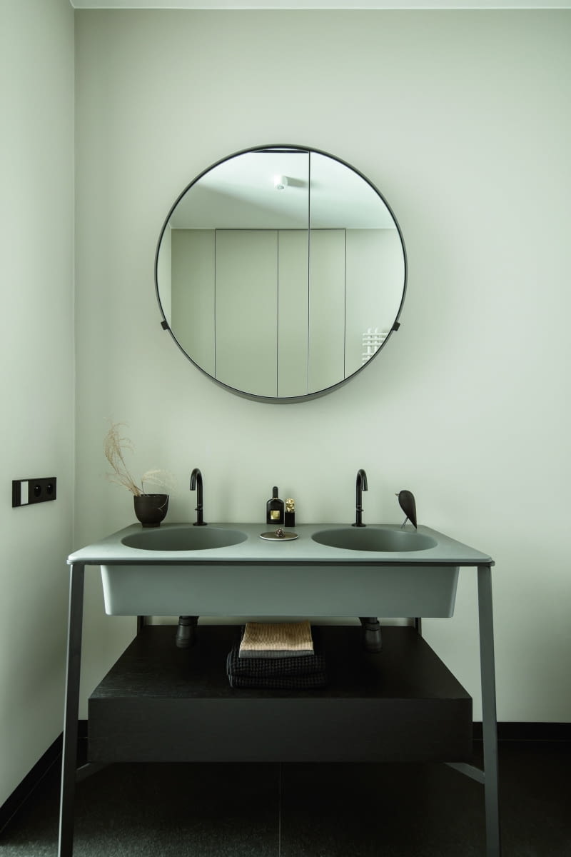 W łazience zaprojektowanej przy sypialni właścicieli funkcję szafki umywalkowej pełni konsola z dwiema umywalkami – model Catino Doppio włoskiej marki Cielo. Ceramiczne misy z blatem wybrano w szarym odcieniu „cemento”, a całość uzupełnia praktyczna, szuflada w czarnym wybarwieniu forniru. W łazience zaprojektowanej przy sypialni właścicieli funkcję szafki umywalkowej pełni konsola z dwiema umywalkami – model Catino Doppio włoskiej marki Cielo. Ceramiczne misy z blatem wybrano w szarym odcieniu „cemento”, a całość uzupełnia praktyczna, szuflada w czarnym wybarwieniu forniru.