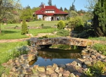 Malownicza willa przytulona do wzgórza ma za tło skarpę porośniętą gęstwiną drzew i krzewów.