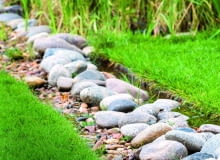 w zagłębieniu terenu położono czarną agrowłókninę i usypano na niej kamienie. Taką 'rynną' nadmiar wody spływa z trawnika. w zagłębieniu terenu położono czarną agrowłókninę i usypano na niej kamienie. Taką 'rynną' nadmiar wody spływa z trawnika.