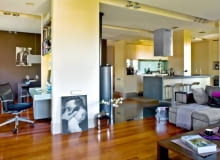 <b> WOKÓŁ KOMINKA. Mąż robi kawę, żona pracuje przy komputerze, dziecko ogląda bajkę. Rodzina jest razem, ale każdy może robić coś innego, nie przeszkadzając reszcie domowników. To efekt umiejętnego podziału przestrzeni dziennej na strefy funkcjonalne. </b> Otwarta część dzienna zajmuje aż dwie trzecie całego mieszkania - niecałe 60 m kw. Urządzono ją tak, by rodzina mogła przebywać razem, mając zapewnione dobre warunki nie tylko do odpoczynku, ale również do pracy. Po połączeniu kuchni z pokojem na środku wnętrza pozostał komin, który został pomysłowo obudowany - powstało tu m.in. miejsce na komputer. Konstrukcja ta umownie wyznacza podział na poszczególne strefy: wypoczynkową, kuchenną i jadalną. Odrębność funkcji podkreśla podłoga ułożona z trzech różnych materiałów (drewno, kamień i płytki gresu). Granicę między kuchnią a kątem wypoczynkowym dodatkowo zaznaczają reflektorki halogenowe zainstalowane w wąskiej długiej wnęce w podwieszanym suficie. <BR /> W aneksie kuchennym zaplanowano wiele schowków ułatwiających utrzymanie porządku: ciąg szafek dolnych i górnych, sięgającą sufitu zabudowę przy bocznej ścianie oraz wyspę z szafką w formie słupa, przesłaniającą zlewozmywak. Do fornirowanych bielonym dębem frontów mebli dobrano kontrastujący blat z granitu. Podłogę w kuchni wyłożono praktycznym gresem.