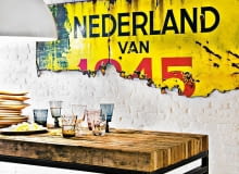 Ceglana ściana pomalowana na biało nie przytłacza wnętrza. Stół na metalowej konstrukcji, z grubym drewnianym blatem (tutaj z desek położonych na sztorc) to mebel prawie obowiązkowy. Do kompletu proste talerze z drewna mango, 36 zł/szt., Square Space styl loftowy, wnętrza loftowe, ceglana ściana, stół na metalowej konstrukcji, Square Space