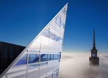 Warszawa przykryta chmurami. Ponad nimi wyłącznie fragmenty najwyższych budynków. Widok z ostatnich pięter apartamentowca Złota 44 na zegar na szczycie Pałacu Kultury jest absolutnie wyjątkowy.