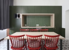 Na aranżację kuchni świetnie wpływa kontrast między zieloną zabudową, a czerwonymi krzesłami. Oryginalne mieszkanie w Krakowie