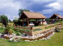 Zagroda- -skansen. Pod wiatami krytymi trzcinową strzechą właściciel gromadzi stary, nieużywany sprzęt rolniczy. OGROD SKANSEN