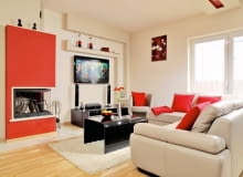 Gospodarze postawili projektantce tylko jeden warunek - w domu ma być dużo czerwieni, bo to ulubiona barwa pani domu. Okazało się, że świetnie pasuje ona do jasnego drewna i kremowych ścian. Od mocnej kolorystyki można odetchnąć tylko w sypialni i jednej z łazienek, gdzie nie ma czerwonych akcentów. <BR /> WNĘTRZA. Czerwień - kolorystyczny motyw przewodni - zestawiono z beżem (ściany, obicie mebli) i czernią urządzeń i hartowanego szkła (stolik kawowy i blat szafki RTV). Warto zwrócić uwagę na podwieszany sufit z czerwonym pasem i na oryginalną obudowę kominka - konstrukcję z płyt gipsowo-kartonowych pomalowano na czerwono. OLYMPUS DIGITAL CAMERA