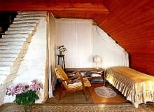 Na strychu wokół rozłożystego pobielonego komina urządzono trzy niewielkie sypialnie dla gości. Oddzielają je od siebie jedynie udrapowane jasne tkaniny. Białe ''schodki'' to element konstrukcyjny komina OKOLICE WARSZAWY - DOM EMILII KRAKOWSKIEJ NAD RZEKA SWIDER FOT. RAFAL LIPSKI UWAGA ! PONOWNA PUBLIKACJA ZA ZGODA WLASCICIELKI ! PUBLIKACJA CZTERY KATY NR 9 (144) - 9.2003