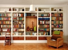 Regał z płyt gipsowo-kartonowych zajmuje całą szerszą ścianę pokoju-biblioteki. Drewniane schodki umożliwiają sięganie po książki z wyższych półek. Wnętrze wydaje się jeszcze większe, niż jest w rzeczywistości. To dzięki jasnej kolorystyce z dominującą bielą w dwóch odcieniach (śnieżnym oraz kremowym), przełamaną barwą podłogi, półek i fotela. regały na książki