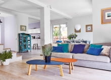 PRZESTRZEŃ I ŚWIATŁO - w tym domu z pewnością ich nie brakuje. Kąt wypoczynkowy od kuchni i jadalni wizualnie oddziela podłoga: w salonie położono bielony dąb szczotkowany, w pozostałej części gres. Szarą kanapę, stoliki kawowe Melisa w odcieniach dżinsu i brandy, zielone i granatowe poduszki oraz osłonki na do- niczki z trawą i rozmarynem kupiono w sklepie Nap.