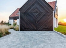 Na tę siedzibę składają się dwa umieszczone obok siebie i połączone przejściem obiekty: pierwszy, większy, to część mieszkalna, usytuowana na dwóch kondygnacjach, a w drugiej, przypominającej wiejską komórkę czy budynek gospodarczy, zlokalizowano garaż. Bramę garażu stworzono z desek z ciemnego modrzewia syberyjskiego, ułożonych w masywny wzór geometryczny, w którym na pierwszy rzut oka trudno dostrzec uchylne skrzydła